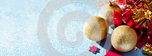 Gorgeous metallic gold christmas baubles, red stars and wrapped present on shiny blue background. Christmas banner.