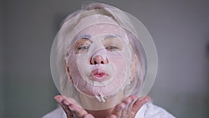 Gorgeous middle aged woman in face mask gesturing air kiss smiling looking at camera. Portrait of confident Caucasian