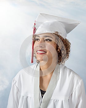 Gorgeous mixed race young lady with curly brown hair in a white cap and gown with red and white tassel