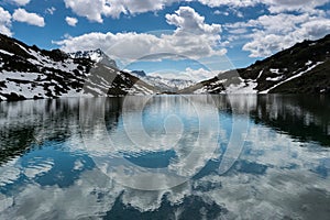 Gorgeous mountain lake in the Alps with reflections and snow remnants