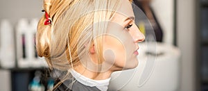 Gorgeous profile of caucasian beauty blonde woman with beautiful hairstyle over hair salon background.