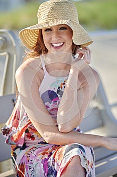 Gorgeous redhead woman poses in print dress at shore