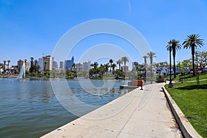 A gorgeous rippling lake with a water fountain surrounded by lush green palm trees and grass with birds