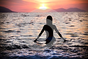Gorgeous fit woman silhouette swimming in sunset.Free happy woman enjoying sunset. Beautiful woman in water embracing the gol