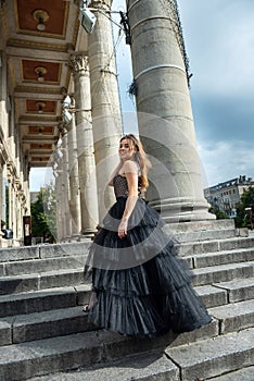 Gorgeous sexy woman in a black dress, standing on the stairs