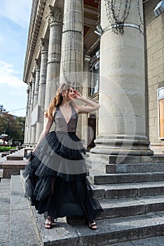 Gorgeous sexy woman in a black dress, standing on the stairs