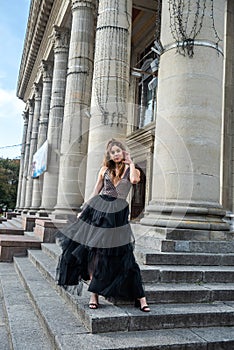 gorgeous sexy woman in a black dress, standing on the stairs