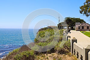 A gorgeous shot of the cliffs and the coastline with vast blue ocean water, lush green hillsides with plants and trees