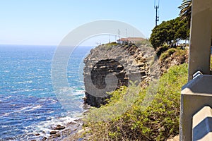 A gorgeous shot of the cliffs and the coastline with vast blue ocean water, lush green hillsides with plants and trees