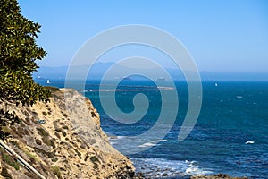 A gorgeous shot of the cliffs and the coastline with vast blue ocean water, lush green hillsides with plants and trees