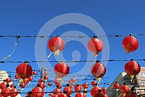 A gorgeous shot of rows of red Chinese lanterns hanging from black cables with a blue sky background at Atlantic Station photo