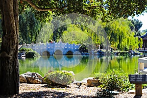 A gorgeous shot of the stone bridge with 3 circles over the green lake surrounded by lush green and autumn colored trees