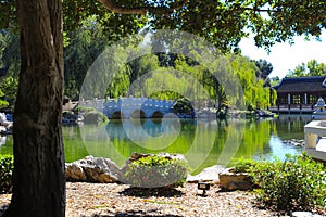 A gorgeous shot of the stone bridge with 3 circles over the green lake surrounded by lush green and autumn colored trees