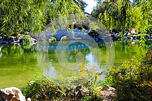 A gorgeous shot of the stone bridge with 3 circles over the green lake surrounded by lush green and autumn colored trees