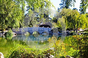 A gorgeous shot of the stone bridge with 3 circles over the green lake surrounded by lush green and autumn colored trees