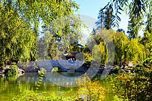 A gorgeous shot of the stone bridge with 3 circles over the green lake surrounded by lush green and autumn colored trees