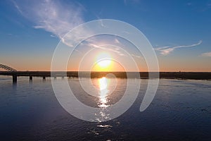 A gorgeous shot of the vast flowing water of the Mississippi river with a stunning blue, yellow and red sunset in the sky