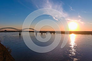 A gorgeous shot of the vast flowing water of the Mississippi river with a stunning blue, yellow and red sunset in the sky