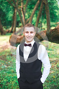 Gorgeous smiling groom. Handsome groom at wedding tuxedo smiling and waiting for bride.Elegant man in black costume and bow-tie.