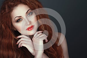 Gorgeous smiling red headed woman with beautiful make up, her hands crossed under her chin