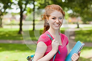 Gorgeous smiling student holding notebooks looking at camera