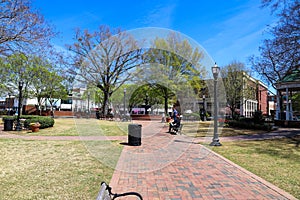 A gorgeous spring day in the Marietta Square with a red brick footpath surrounded by lush green trees, plants and grass