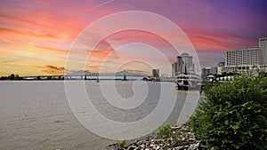 a gorgeous spring landscape along the Mississippi River with boats sailing and the Crescent City Connection bridge with hotels