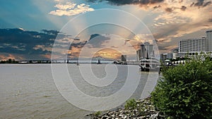 a gorgeous spring landscape along the Mississippi River with boats sailing and the Crescent City Connection bridge with hotels