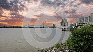 a gorgeous spring landscape along the Mississippi River with boats sailing and the Crescent City Connection bridge with hotels