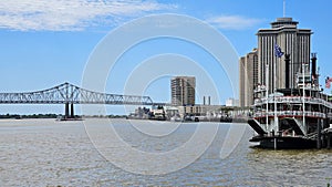 a gorgeous spring landscape along the Mississippi River with boats sailing and the Crescent City Connection bridge with hotels