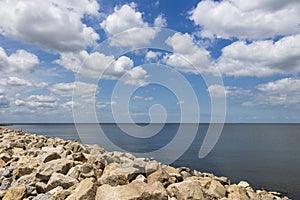 a gorgeous spring landscape at Breakwater Park with ocean water, rocks, blue sky and clouds in New Orleans Louisiana