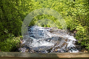 a gorgeous spring landscape with a flowing waterfall and rocks, lush green trees, grass and plants at Amicalola Falls State Park