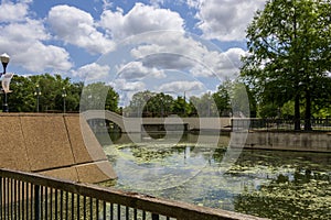 a gorgeous spring landscape at Louis Armstrong Park with lush green trees, plants and grass, a lake, blue sky and clouds