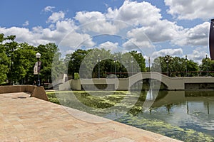 a gorgeous spring landscape at Louis Armstrong Park with lush green trees, plants and grass, a lake, blue sky and clouds