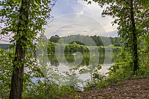 a gorgeous spring landscape at Proctor Landing Park at sunset with rippling water, lush green trees and plants, blue sky