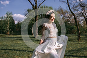 Gorgeous stylish dark-haired bride in a beautiful, white dress walks in the park