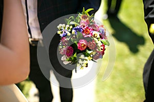 gorgeous stylish elegant groom and best man holding colorful bouquets