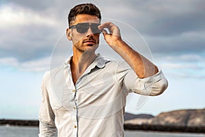 Gorgeous stylish man wearing fashionable shirt and sunglasses. City style