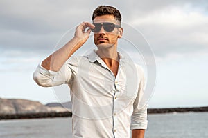 Gorgeous stylish man wearing fashionable shirt and sunglasses. City style