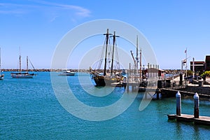 A gorgeous summer day at the harbor with boats and yachts docked in vast deep blue ocean water