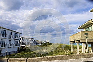 A gorgeous summer landscape along the coastline with homes and lush green plants and grass, blue ocean water, blue sky photo