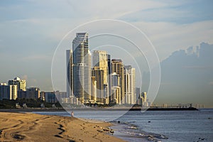 A gorgeous summer landscape at the beach with hotels, condos and skyscrapers in the city skyline at sunrise with birds on the sand