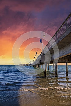 A gorgeous summer landscape at the Belmont Veterans Memorial Pier with blue ocean water and waves rolling into the beach