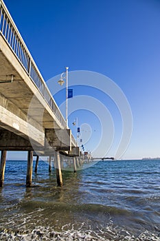 A gorgeous summer landscape at the Belmont Veterans Memorial Pier with blue ocean water and waves rolling into the beach