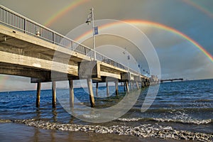 A gorgeous summer landscape at the Belmont Veterans Memorial Pier with blue ocean water and waves rolling into the beach