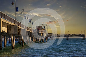 A gorgeous summer landscape at the Belmont Veterans Memorial Pier with blue ocean water and waves rolling into the beach