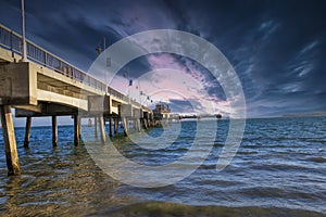 A gorgeous summer landscape at the Belmont Veterans Memorial Pier with blue ocean water and waves rolling into the beach