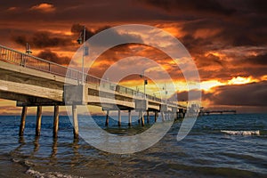 A gorgeous summer landscape at the Belmont Veterans Memorial Pier with blue ocean water and waves rolling into the beach