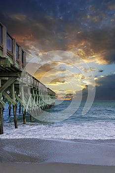 A gorgeous summer landscape at Crystal Pier with blue ocean water, brown sand, waves and powerful clouds at sunset