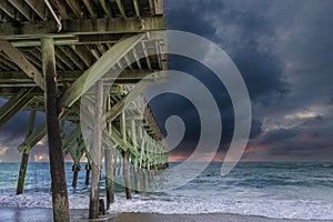 A gorgeous summer landscape at Crystal Pier with blue ocean water, brown sand, waves and powerful clouds at sunset